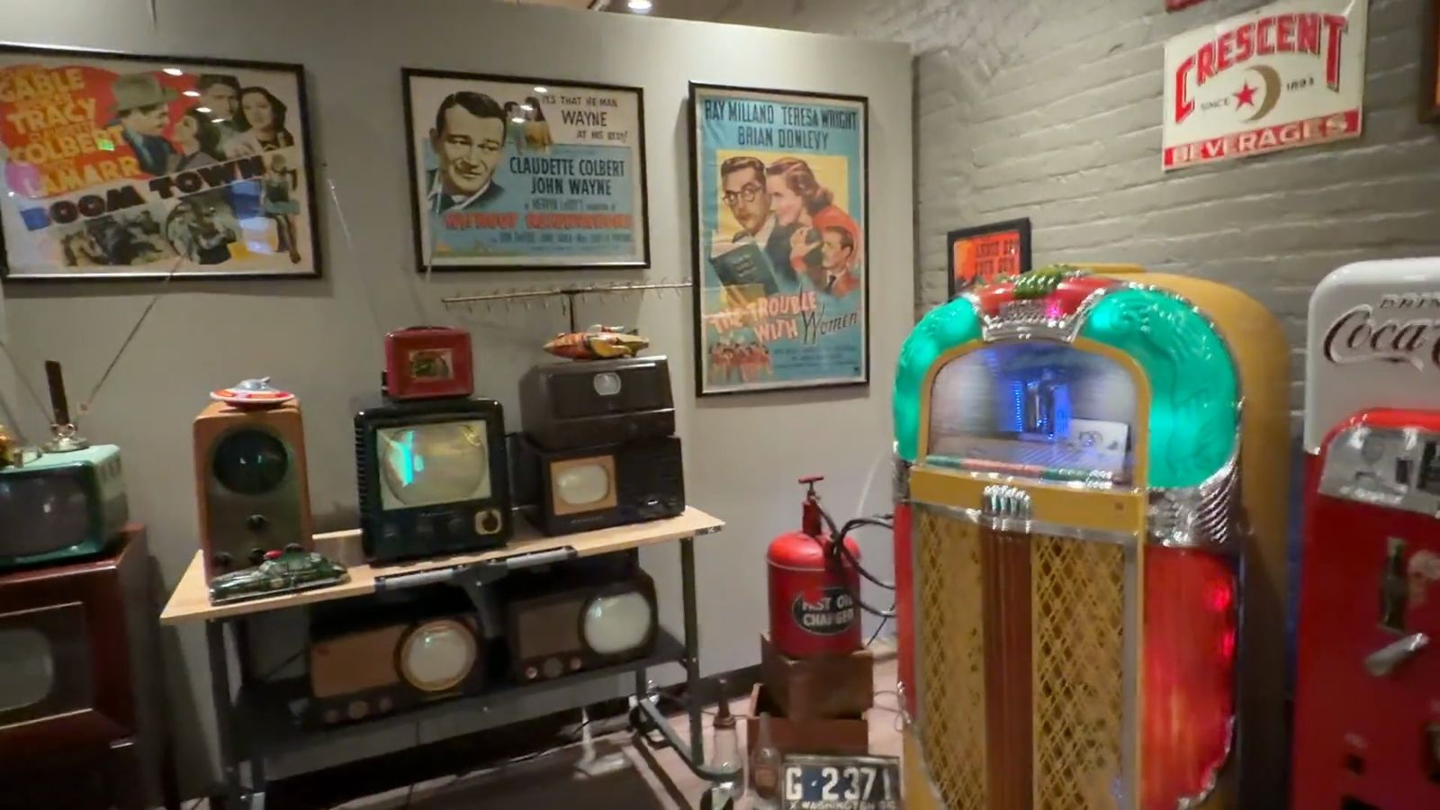 Old televisions on a table beside a glowing jukebox in the Beautiful Things gallery