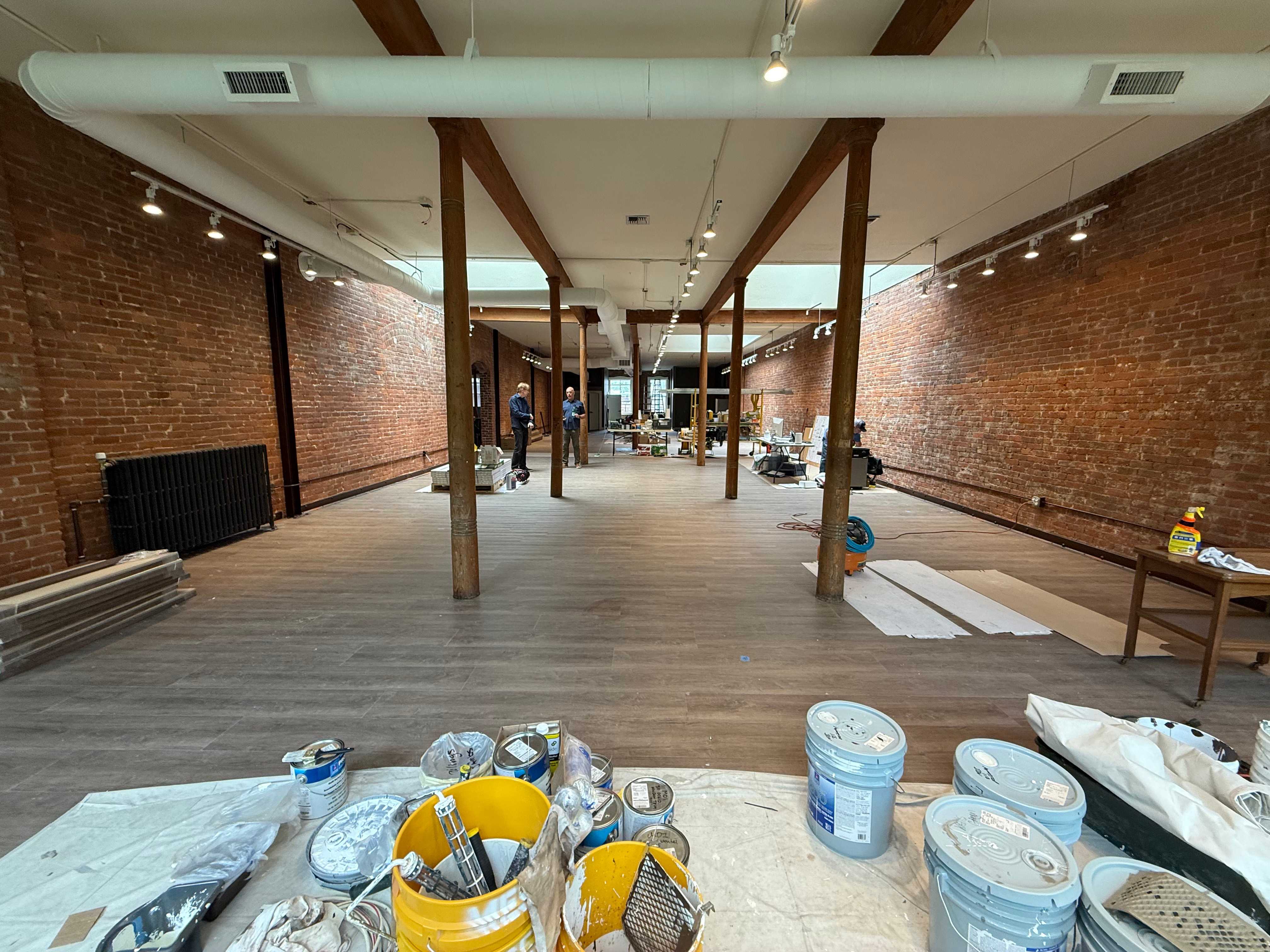 Interior view of the atelier space under construction, showing large skylights and brick walls